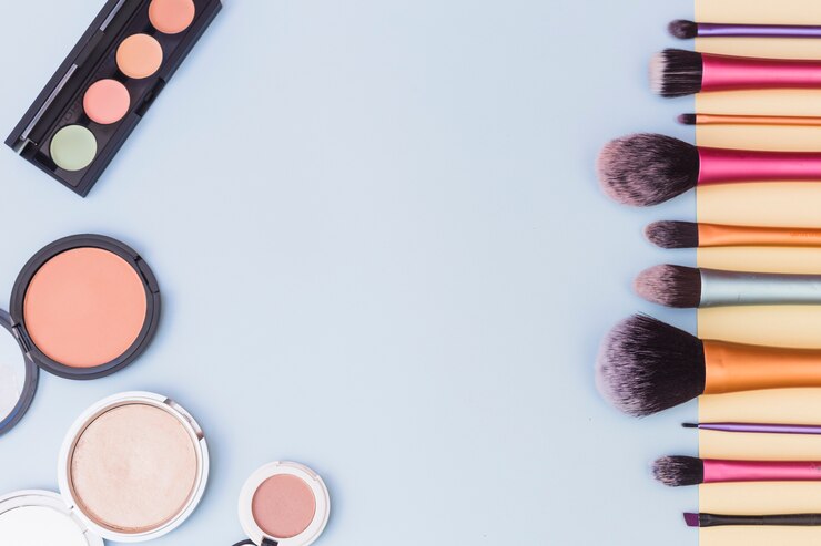 Foto gratuito una vista aérea de la paleta de sombras de ojos; colorete y pinceles de maquillaje sobre fondo azul