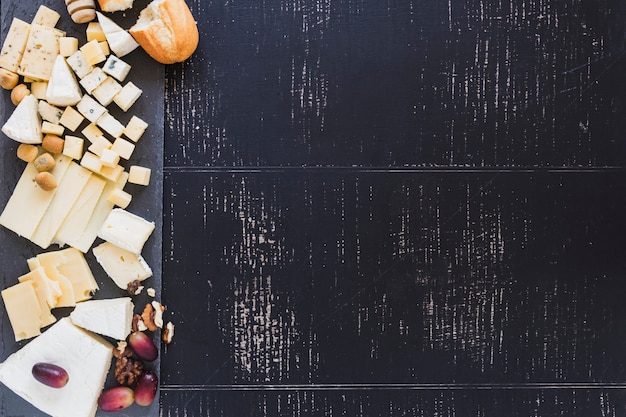 Foto gratuita una vista aérea de pan con diferentes tipos de queso con uvas sobre fondo negro con textura