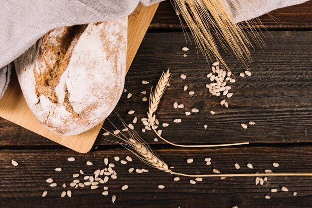 Una vista aérea de pan y espiga de trigo con semillas de girasol en mesa de madera