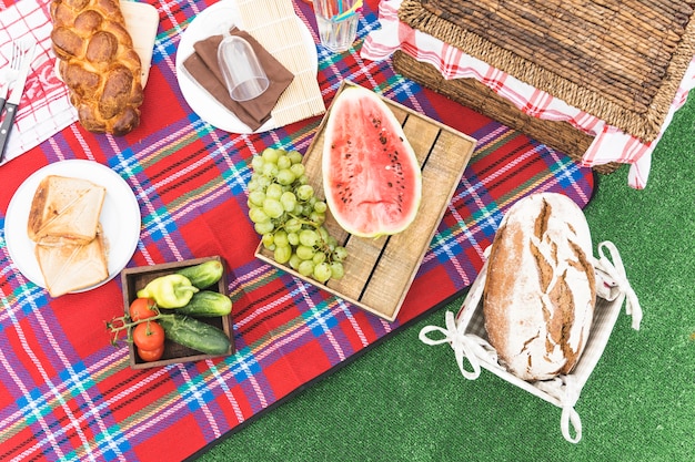 Foto gratuita una vista aérea de pan horneado; canasta de frutas y picnic en manta.