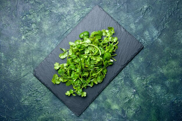 Vista aérea del paquete de cilantro sobre tabla de cortar de madera sobre fondo verde negro de colores mezclados con espacio libre