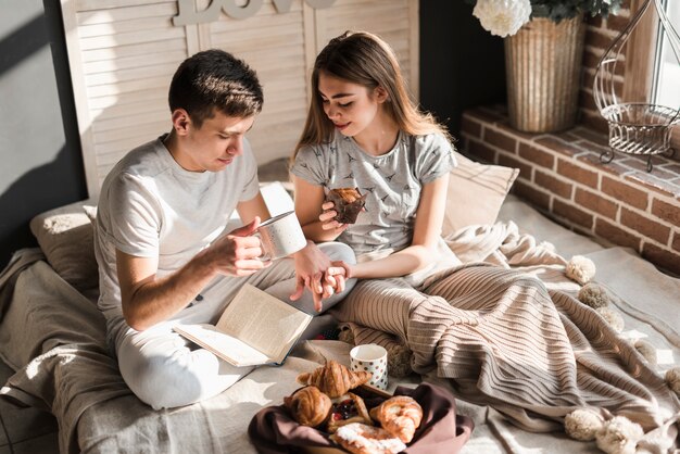 Una vista aérea de una pareja sentada en la cama con una taza de café y un muffin