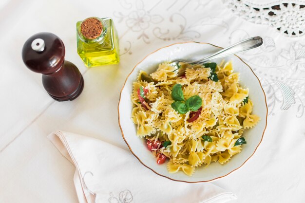 Una vista aérea de pasta farfalle con queso; Tomates y hojas de albahaca en placa