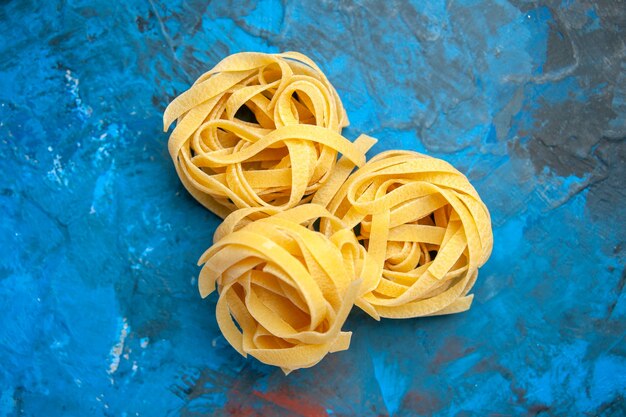 Vista aérea de pastas de tallarines frescos caseros sobre fondo azul.