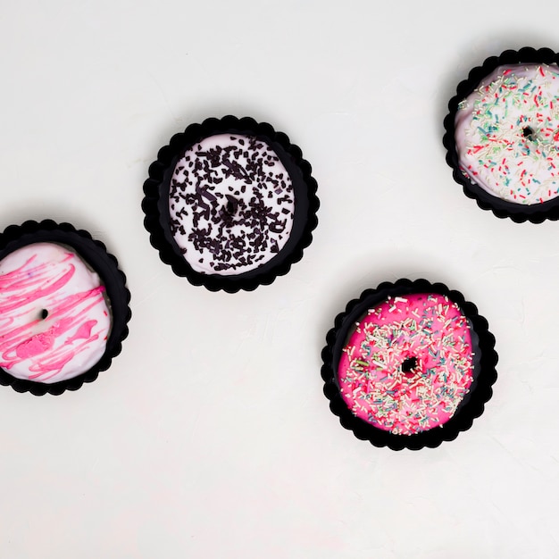 Una vista aérea de pequeños donuts en soporte de papel marrón sobre fondo blanco