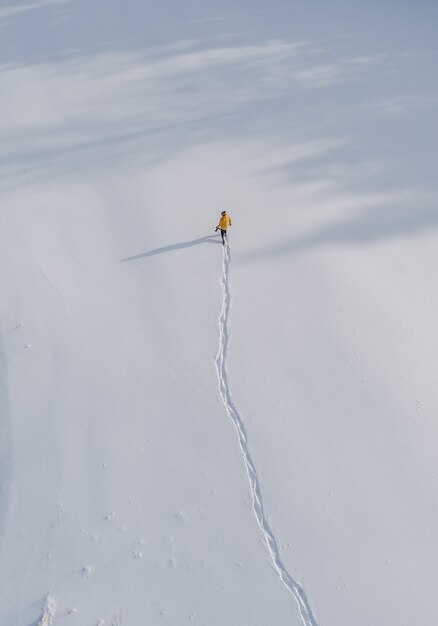 Vista aérea de una persona caminando en un campo cubierto de nieve