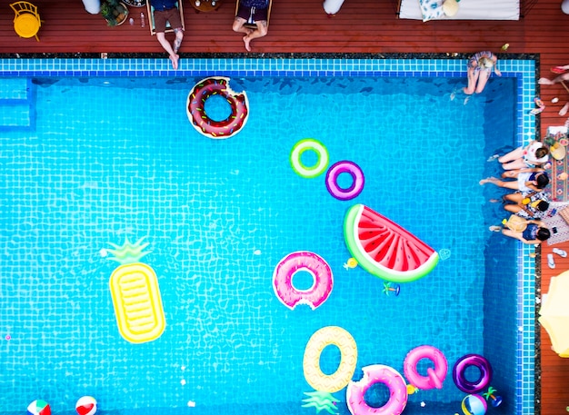 Vista aérea de personas disfrutando de la piscina con coloridos flotadores inflables