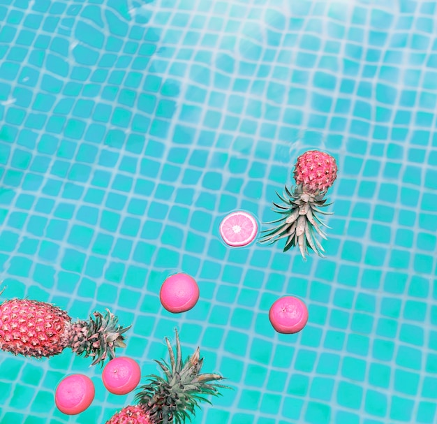 Vista aérea de piña y naranjas flotando en una piscina