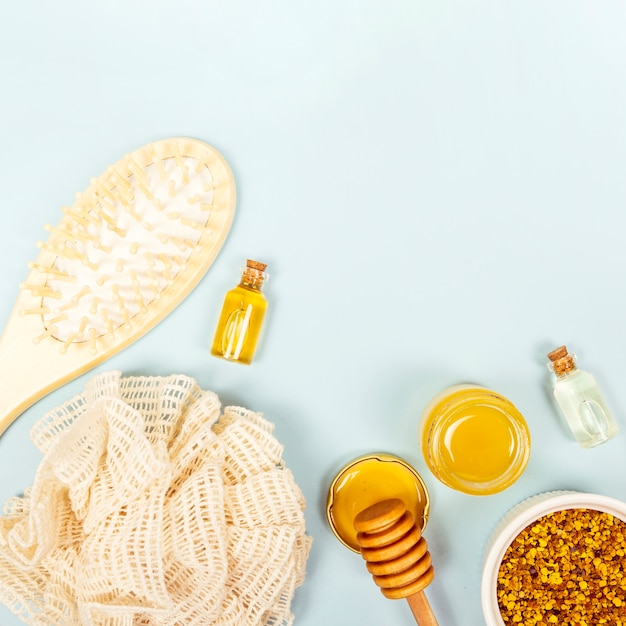 Vista aérea del pincel; botella de aceite esencial; tarro de miel polen de abeja y esponja vegetal