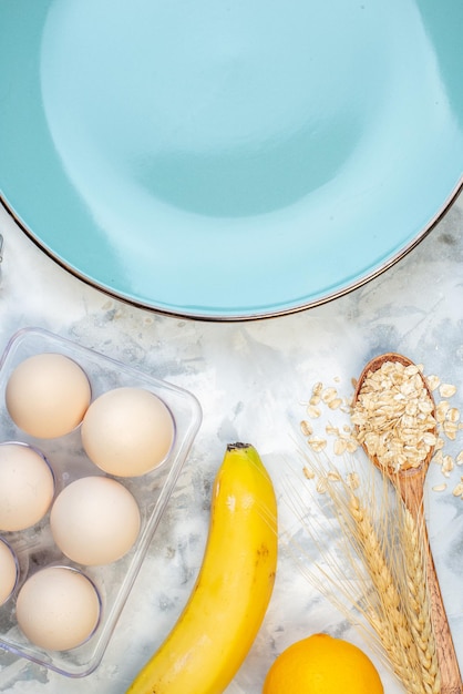 Vista aérea del plato azul vacío y los ingredientes para la comida saludable sobre fondo de hielo