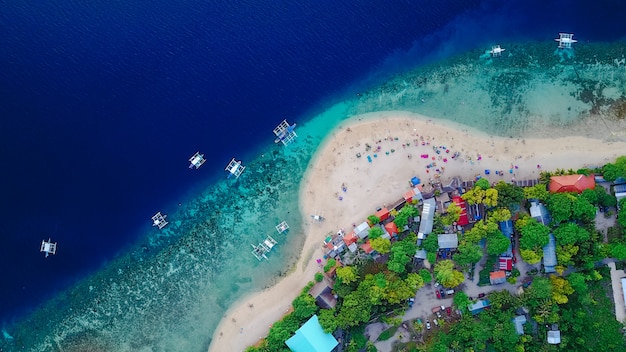 Vista aérea de la playa de arena con los turistas nadando en la hermosa agua de mar claro de la playa de la isla de Sumilon aterrizando cerca de Oslob, Cebú, Filipinas. - Aumentar el procesamiento de color.