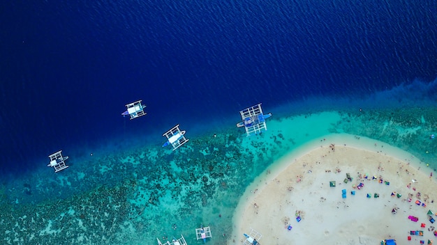 Vista aérea de la playa de arena con los turistas nadando en la hermosa agua de mar claro de la playa de la isla de Sumilon aterrizando cerca de Oslob, Cebú, Filipinas. - Aumentar el procesamiento de color.