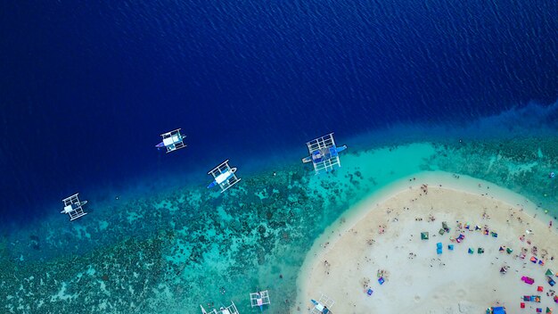 Vista aérea de la playa de arena con los turistas nadando en la hermosa agua de mar claro de la playa de la isla de Sumilon aterrizando cerca de Oslob, Cebú, Filipinas. - Aumentar el procesamiento de color.