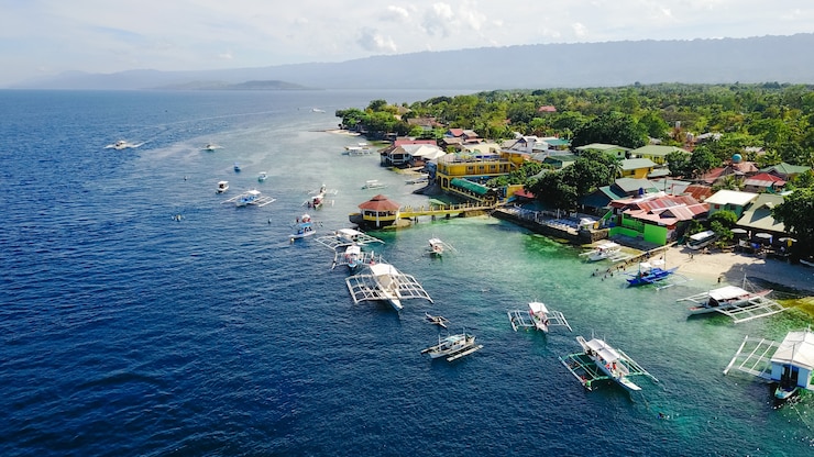 Foto gratuito vista aérea de la playa de arena con los turistas nadando en la hermosa agua de mar claro de la playa de la isla de sumilon aterrizando cerca de oslob, cebú, filipinas. - aumentar el procesamiento de color.
