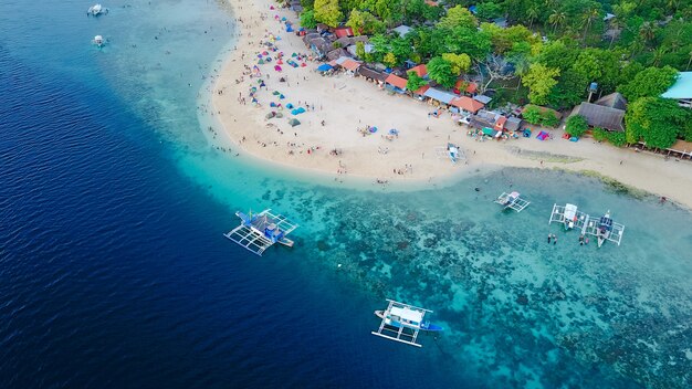 Vista aérea de la playa de arena con los turistas nadando en la hermosa agua de mar claro de la playa de la isla de Sumilon aterrizando cerca de Oslob, Cebú, Filipinas. - Aumentar el procesamiento de color.