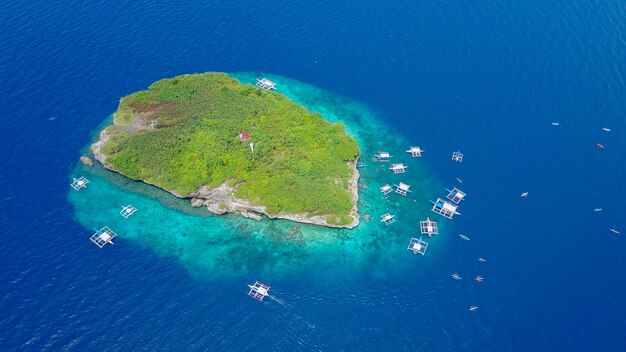 Vista aérea de la playa de arena con los turistas nadando en la hermosa agua de mar claro de la playa de la isla de Sumilon aterrizando cerca de Oslob, Cebú, Filipinas. - Aumentar el procesamiento de color.