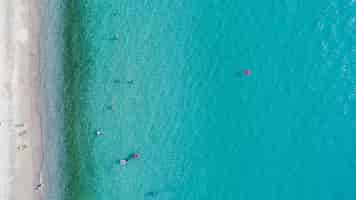 Foto gratuita vista aérea de la playa de arena con turistas nadando.