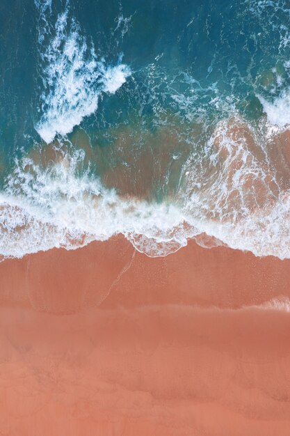 Vista aérea de la playa rosa y las olas del mar azul.