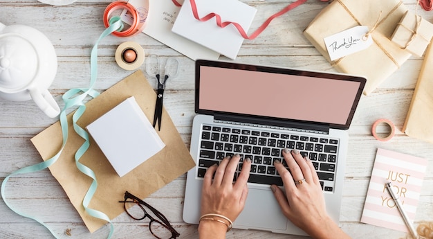 Vista aérea del primer de manos usando la computadora portátil y la tableta con regalos envueltos