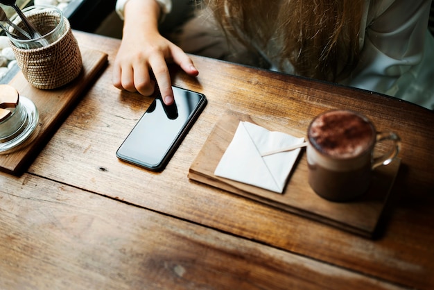 Vista aérea del primer de la mujer que se sienta en café usando el teléfono móvil