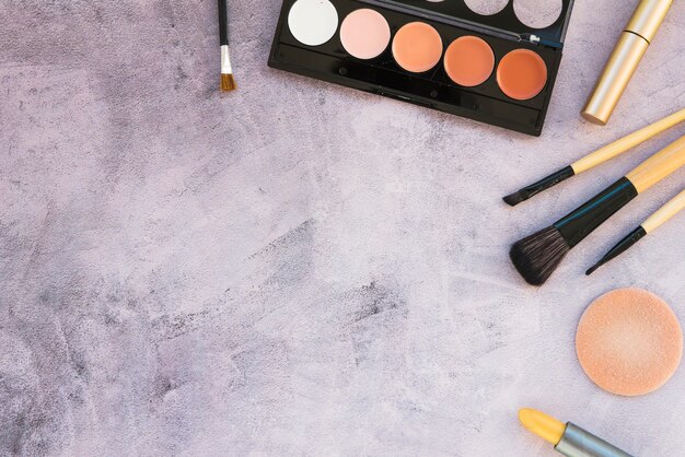 Una vista aérea de productos de belleza para maquillaje profesional sobre fondo de hormigón.