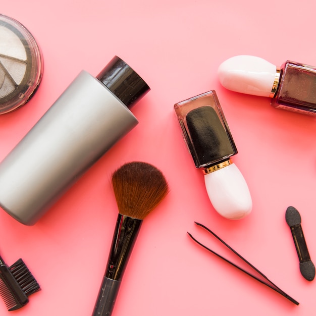 Una vista aérea de productos de maquillaje de cosméticos en fondo rosa