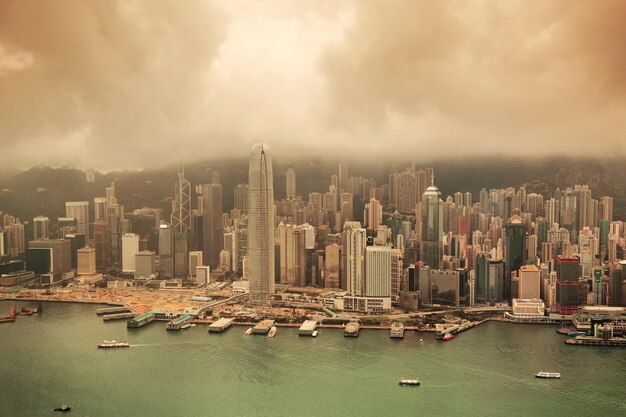 Vista aérea del puerto Victoria y horizonte en Hong Kong con rascacielos urbanos en tono amarillo.