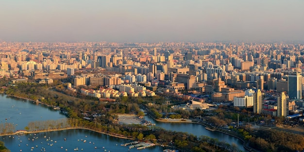 Vista aérea de la puesta de sol de Beijing con edificios urbanos y lago.