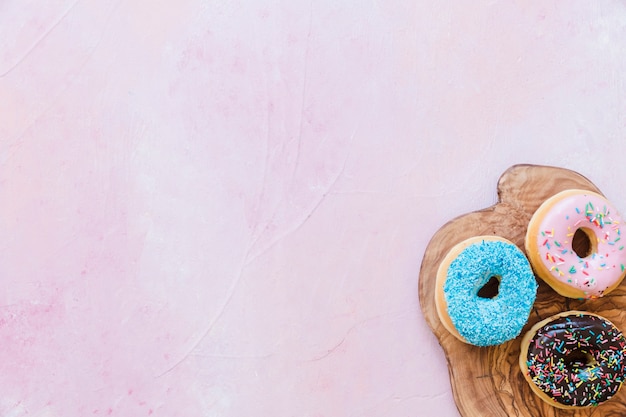 Vista aérea de sabrosos donuts en tabla de cortar de madera