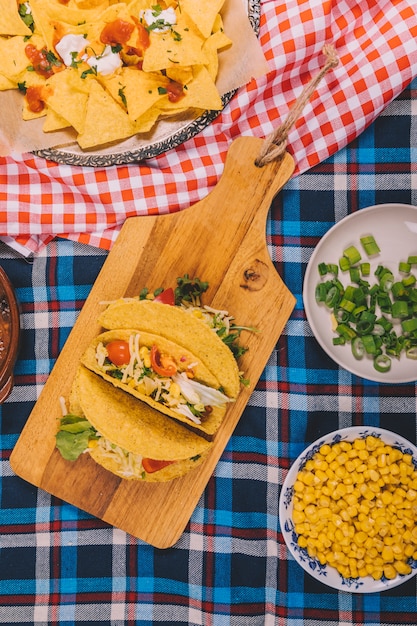 Vista aérea de sabrosos nachos mexicanos y tacos en mantel