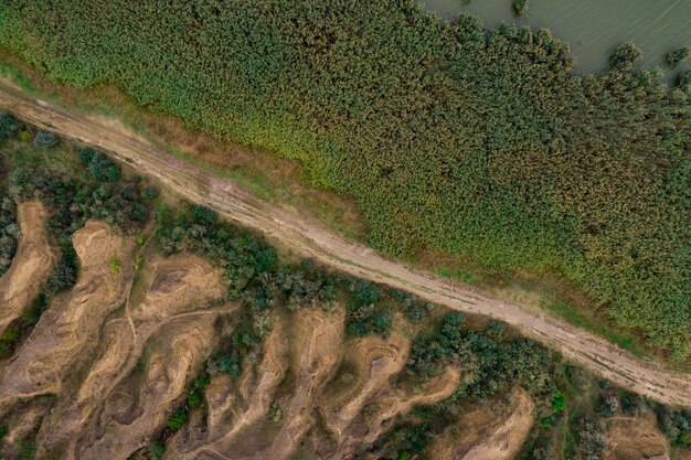 Vista aérea superior de la carretera de campo que divide grinery y dunas de arena.