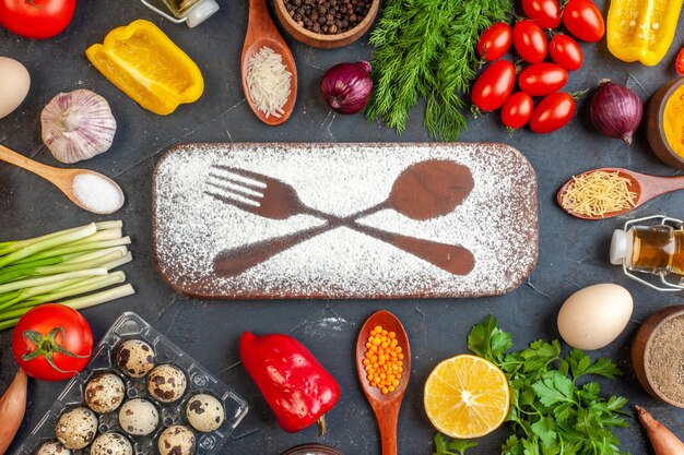 Vista aérea de la tabla de cortar con un cuchillo tenedor de harina dibujado entre verduras frescas diferentes especias