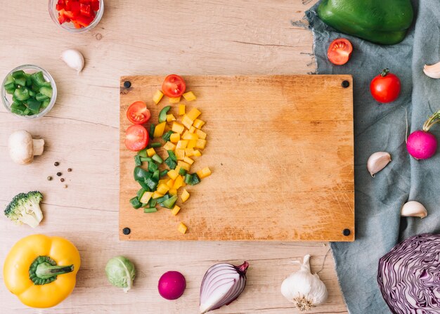 Una vista aérea de la tabla de cortar con verduras picadas en mesa de madera