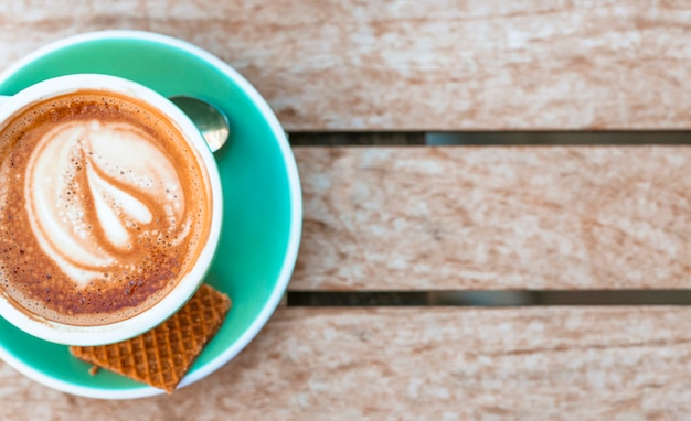 Una vista aérea de la taza de café con latte art en la mesa de madera