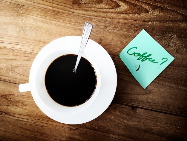 Foto gratuita vista aérea de la taza de café en la mesa de madera con nota adhesiva