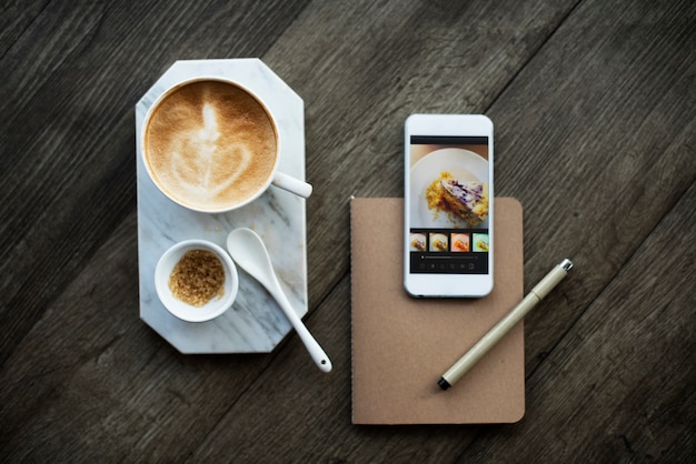 Vista aérea de la taza de café y teléfono móvil en la mesa de madera