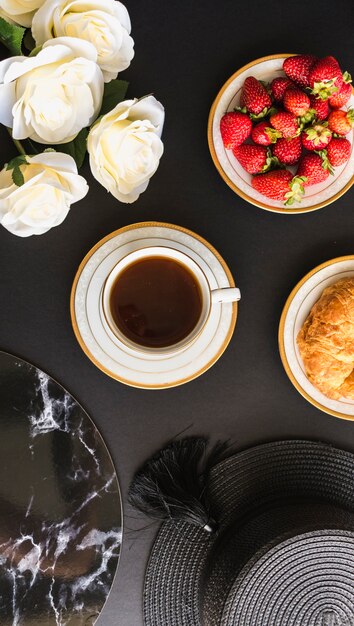 Vista aérea de la taza de té con fresas y pan