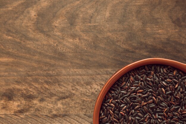 Vista aérea del tazón de arroz negro en la rústica mesa de madera