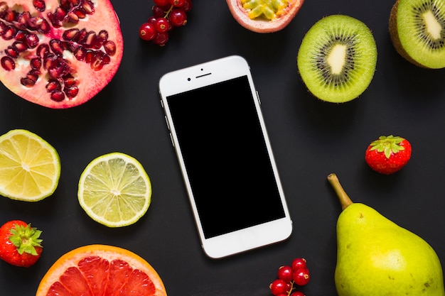 Una vista aérea del teléfono inteligente con muchas frutas sobre fondo negro