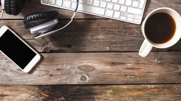 Vista aérea del teléfono móvil; auriculares y teclado con taza de café