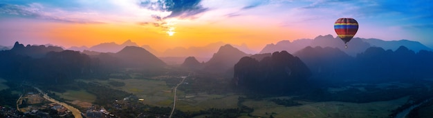 Vista aérea de Vang vieng con montañas y globo al atardecer.