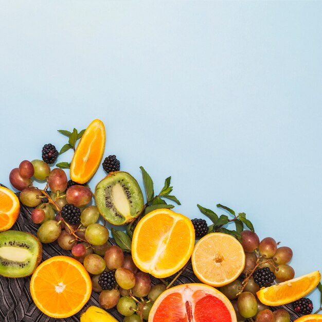 Una vista aérea de varias frutas y uvas a la mitad sobre fondo azul