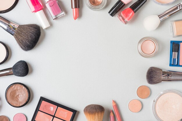 Vista aérea de varios productos de maquillaje que forman una forma circular sobre fondo blanco