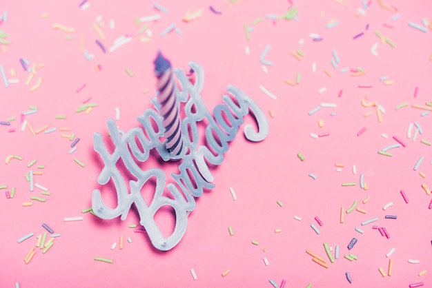 Foto gratuita vista aérea de la vela sobre el texto feliz cumpleaños y espolvorear sobre fondo rosa