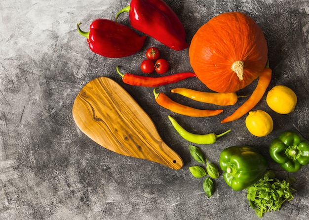 Una vista aérea de verduras de colores y tabla de cortar en el fondo de textura grunge