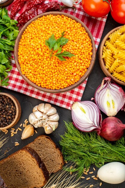 Vista aérea de verduras frescas rebanadas de pan lentejas rojas en un tazón marrón pastas de pimienta