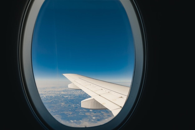 Vista del ala del avión de pasajeros por encima de la tierra desde el interior