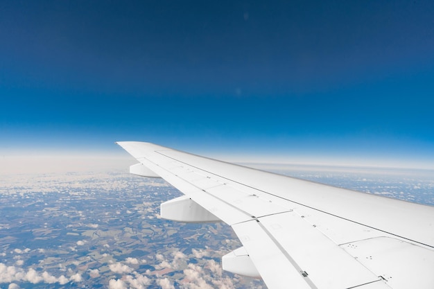 Vista del ala del avión de pasajeros por encima de la tierra desde el interior