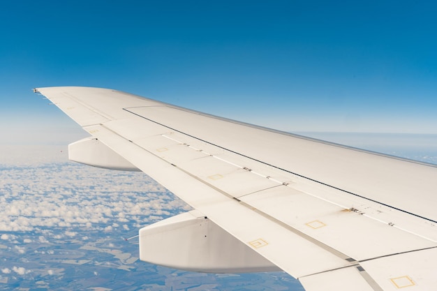 Vista del ala del avión de pasajeros por encima de la tierra desde el interior