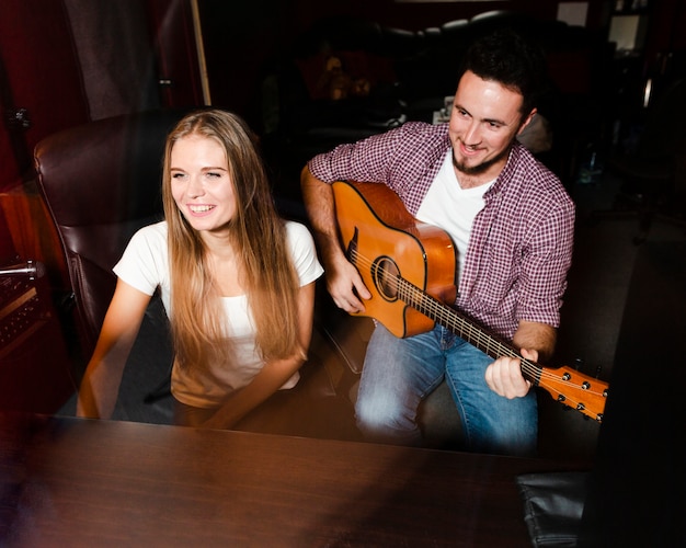 Foto gratuita vista alta hombre tocando la guitarra y sonrisas de mujer